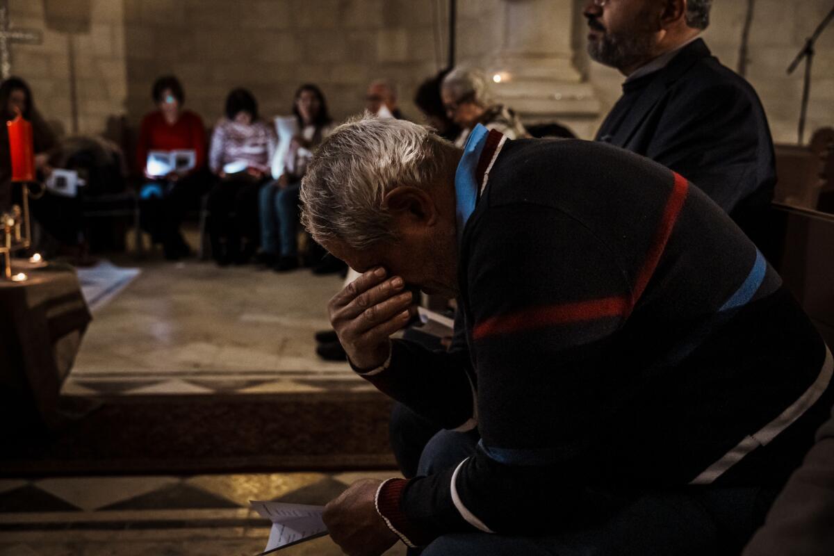 Daher Nassar lowers his head to pray.