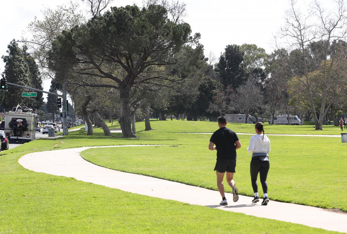 Runners exercise along the perimeter of Mile Square Park on Tuesday in Fountain Valley.