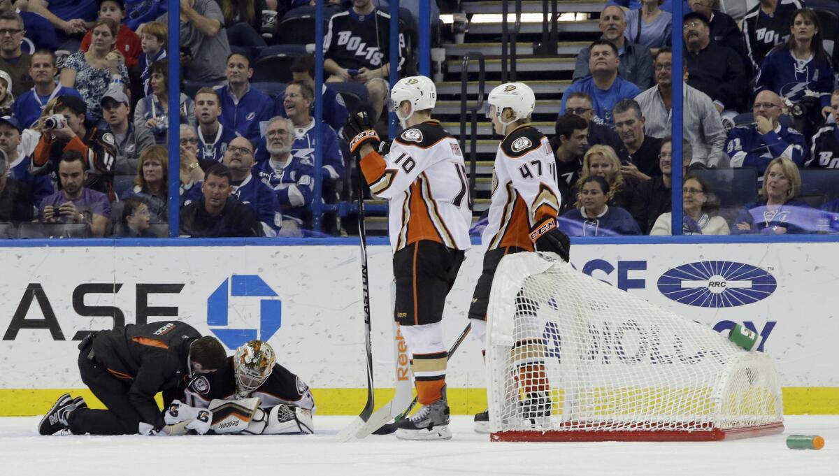 Ducks right wing Corey Perry and defenseman Hampus Lindholm look on as goalie Frederik Andersen is tended to by a trainer Sunday night at Tampa Bay.