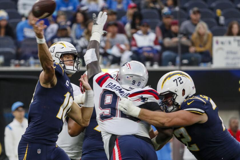 Inglewood, CA, Sunday, October 31, 2021 - Los Angeles Chargers quarterback Justin Herbert (10) passes under pressure against the New England Patriots at SoFi Stadium. (Robert Gauthier/Los Angeles Times)