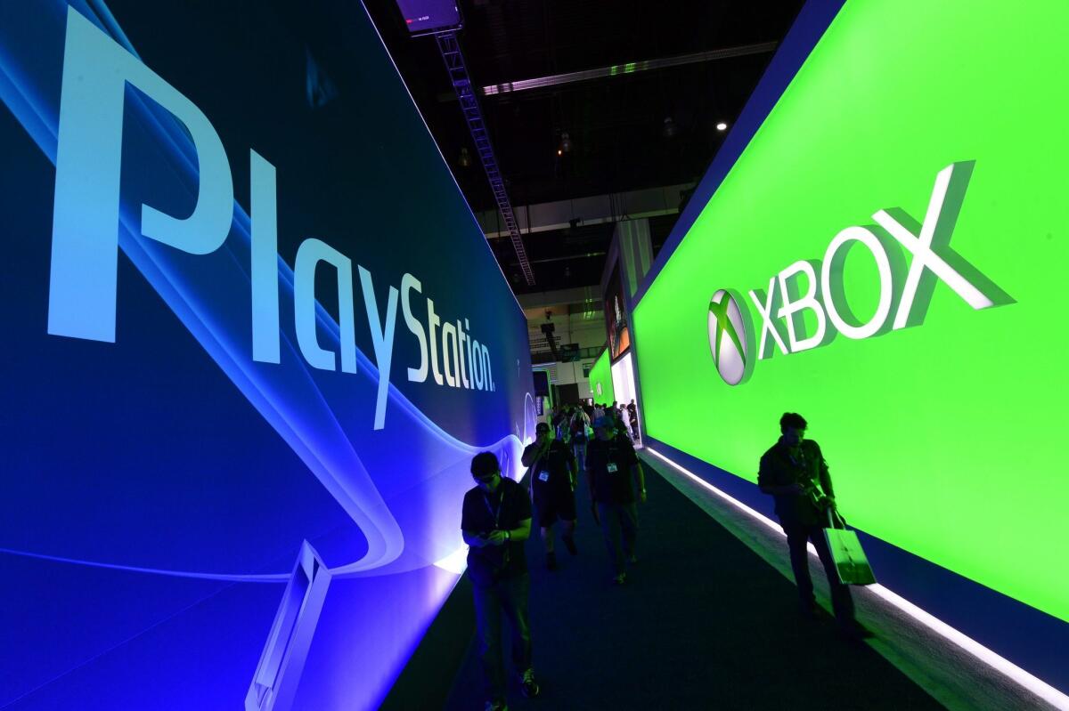 Visitors walk between the Xbox and PlayStation exhibition booths on the opening day of E3 on Tuesday.