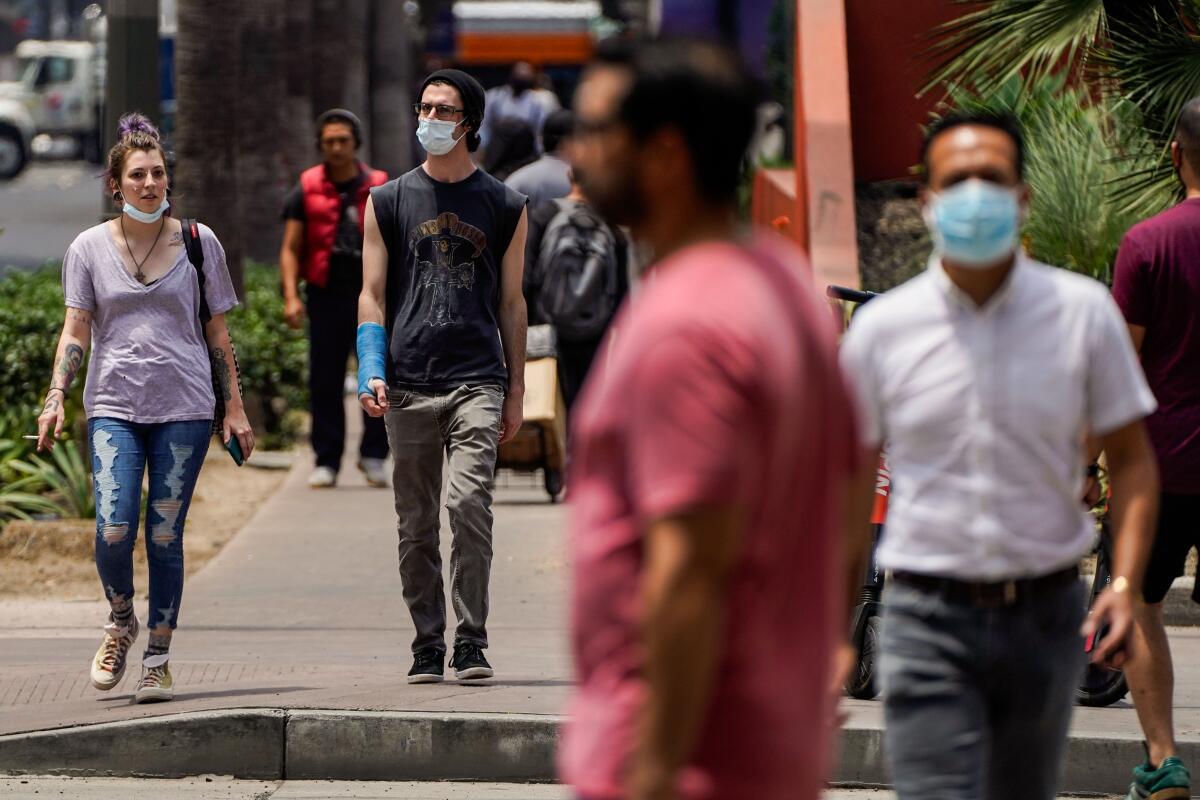 Some pedestrians wear masks, others don't, in downtown Los Angeles on June 25.