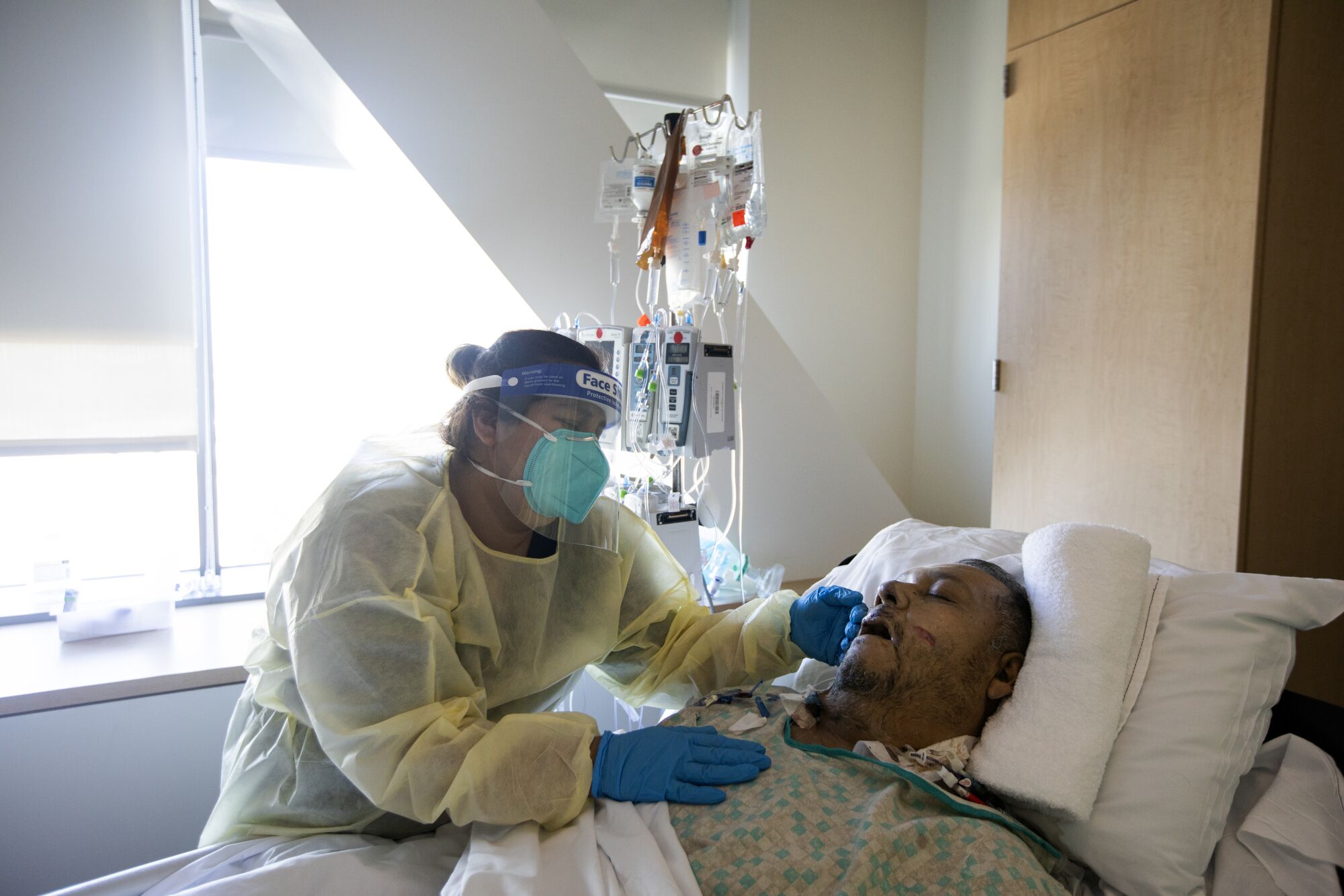 A woman stands at the bedside of a man who has died
