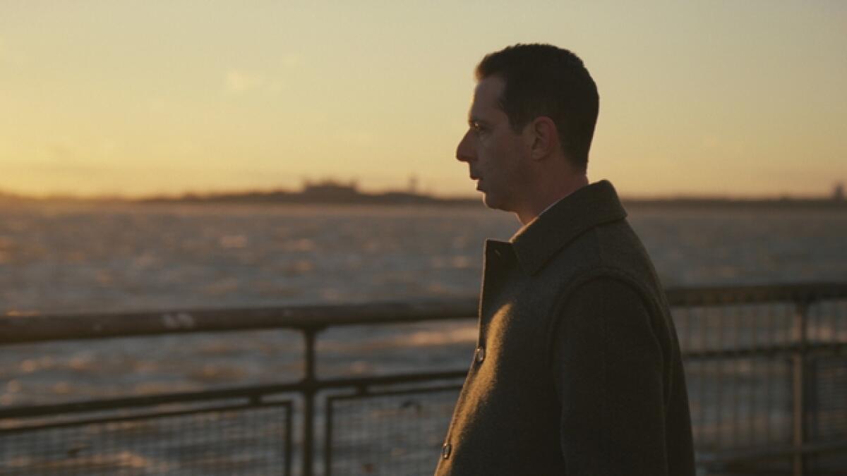 Jeremy Strong (in character as Kendall Roy) looks out over a body of water while wearing a winter coat.