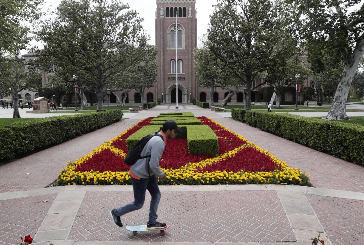 A man rides a skateboard on the USC campus