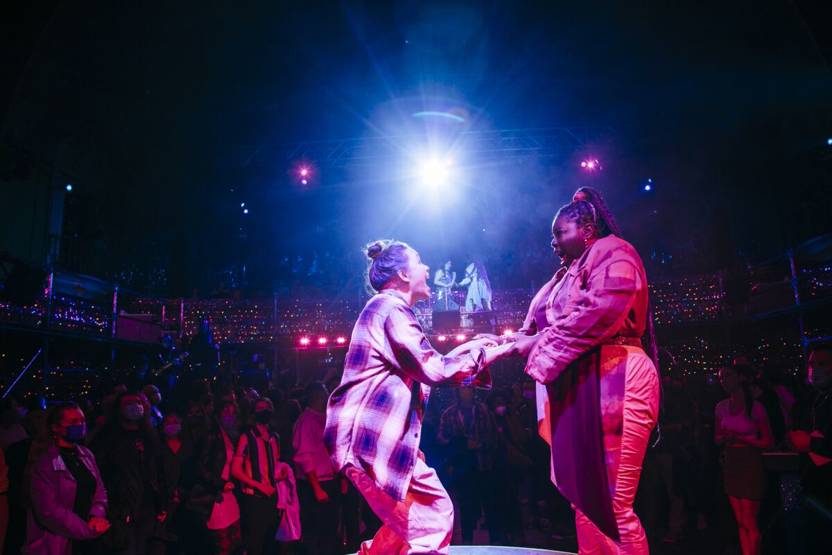 Two women hold hands onstage
