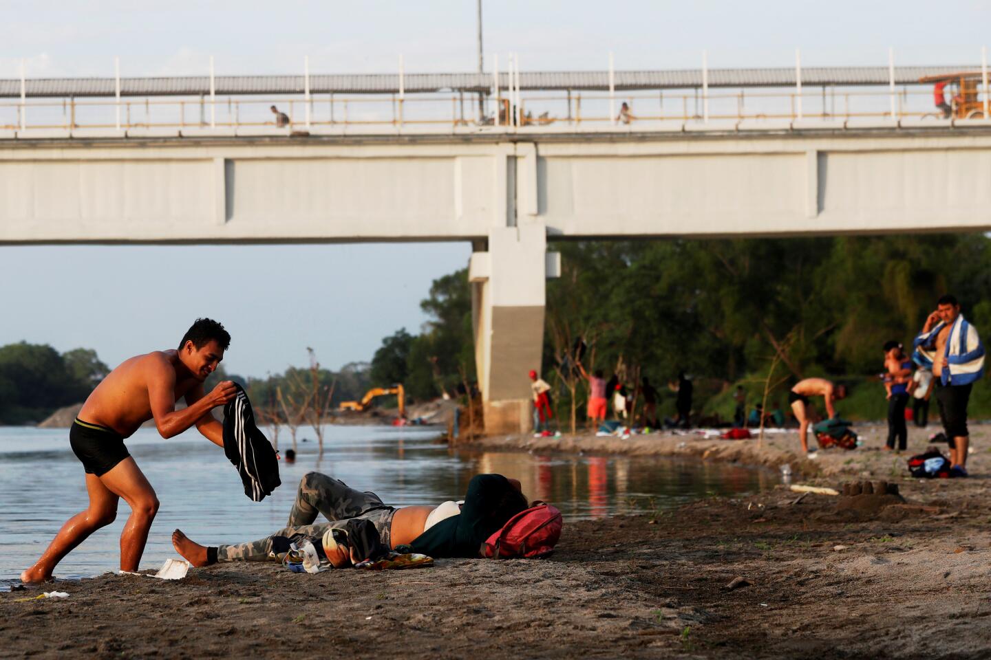 Honduran migrants rest on the banks of the Suchiate River that divides the countries of Guatemala and Mexico, from Tecun Uman, Guatemala.