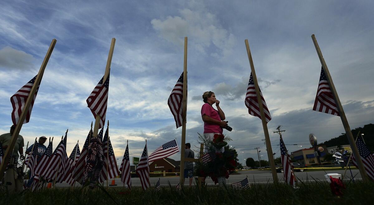 A woman walks past a makeshift memorial with five U.S. flags at the Armed Forces Career Center in Chattanooga, Tenn., on July 21. The memorial honors four Marines and one Navy petty officer killed in a shooting rampage.