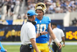 Chargers coach Jim Harbaugh meets quarterback Justin Herbert (10) on the field before their game against the Raiders.