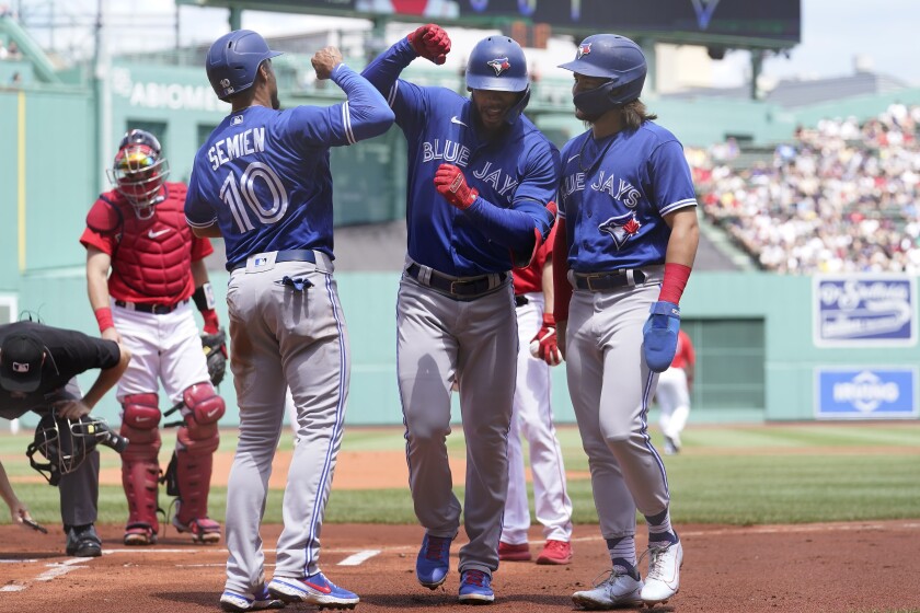 Toronto Blue Jays right fielder Teoscar Hernandez, center right, celebrates with Marcus Semien (10) and Bo Bichette, right, after Hernandez hit a three-run home run in the first inning of a baseball game, as Boston Red Sox's Kevin Plawecki, left, looks on, Sunday, June 13, 2021, in Boston. (AP Photo/Steven Senne)