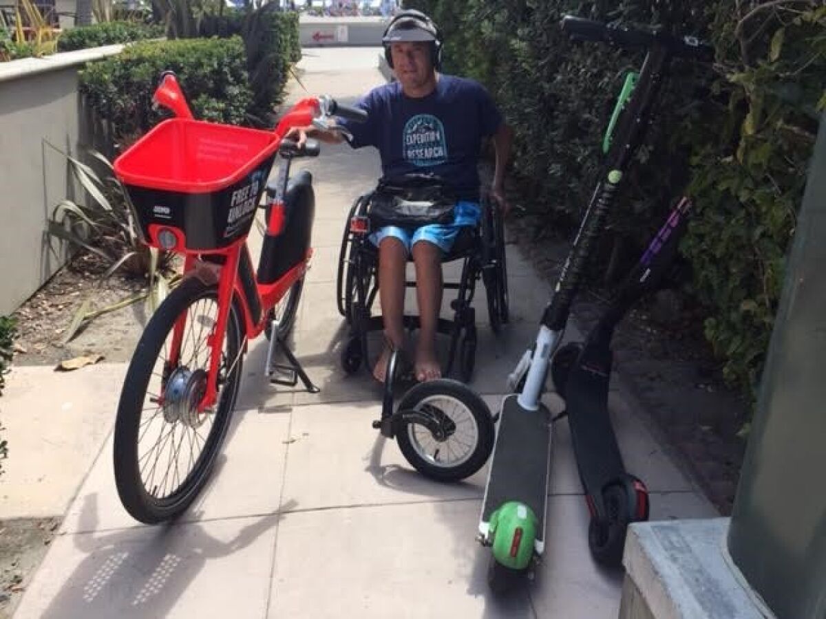 In Mission Beach, a man in a wheelchair tries to navigate around dockless vehicles.