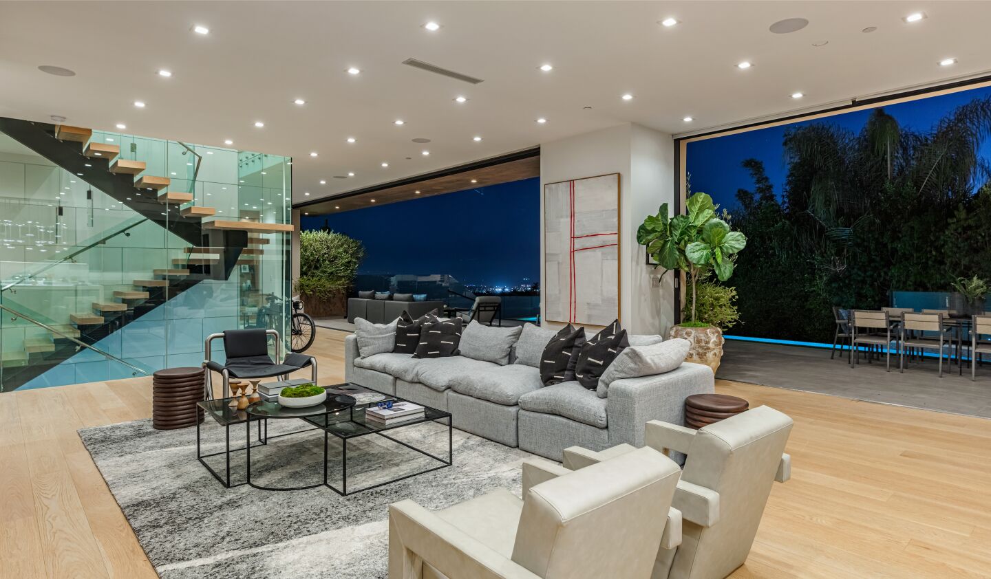 The open floor plan has floor to ceiling windows, furniture and a floating stairway.