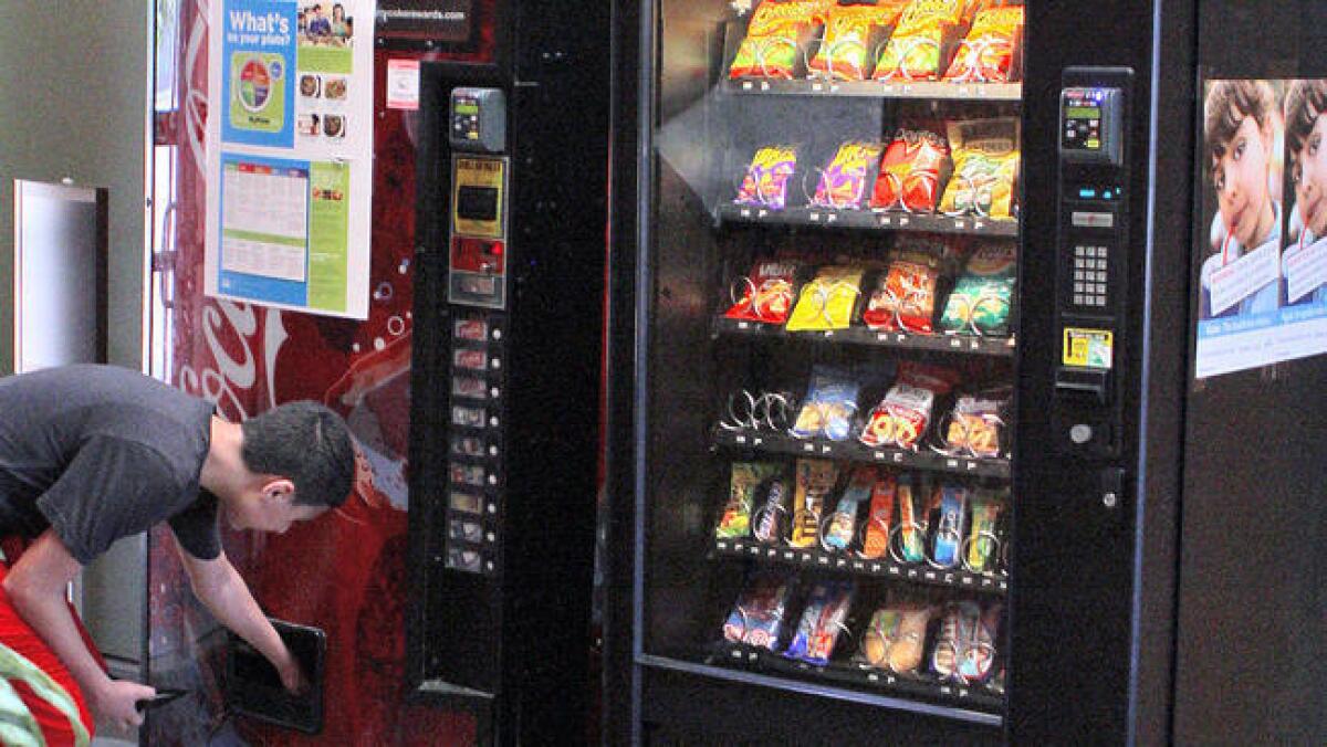 A youth gets a bottle of water from one of the evending machines at the Pacific Community Center and Park in Glendale on Monday, March 28, 2016.