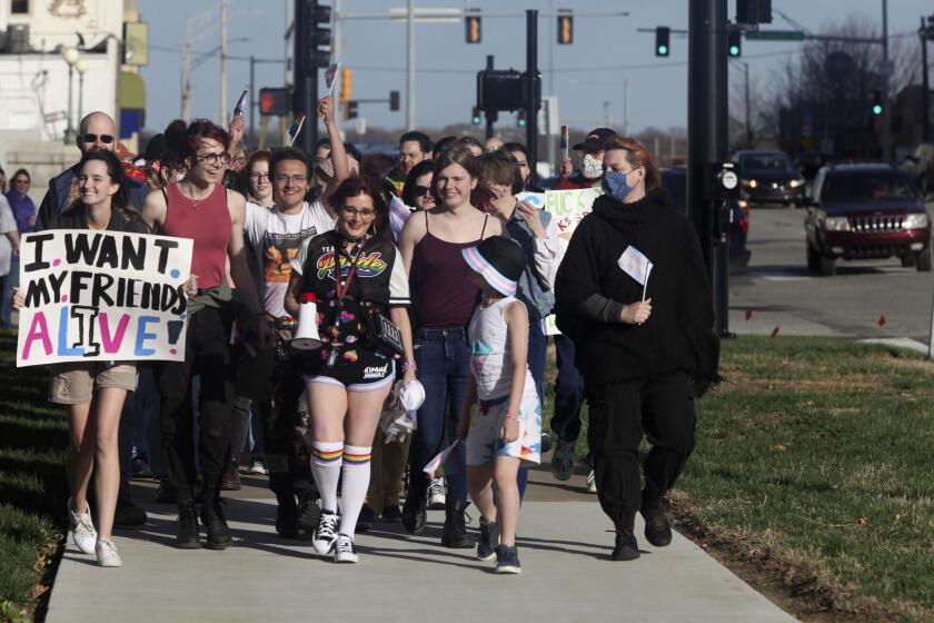 More than 100 people, many of them transgender youth, march around the Kansas Statehouse on the annual Transgender Day of Visibility, Friday, March 31, 2023, in Topeka, Kan. While the event was a celebration of transgender identity, it also was a protest against proposals before the Kansas Legislature to roll back transgender rights. (AP Photo/John Hanna)