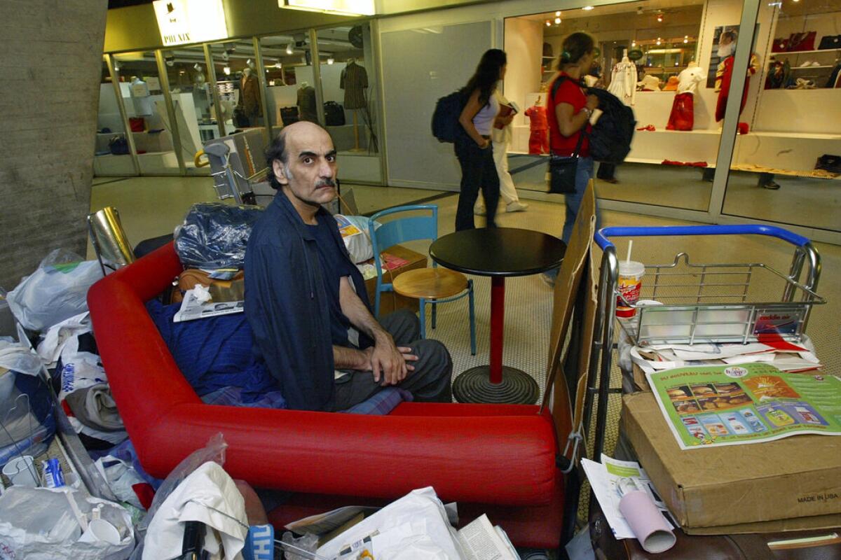 Merhan Karimi Nasseri sentado entre sus pertenencias en la Terminal 1 