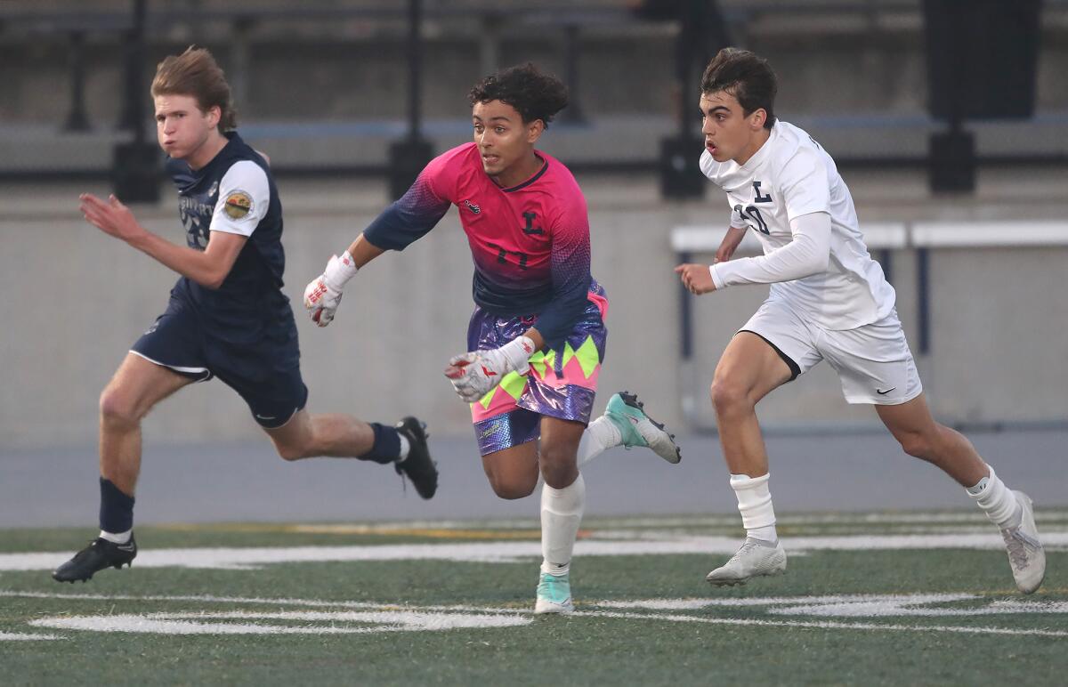 Newport Harbor's Beck Brosnan (21), far left, gets into a foot race with Loyola goalie Kai Campos (77) and Peter Borges (12).