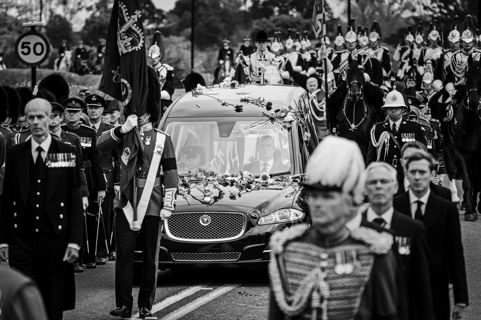 A hearse bearing the coffin of Queen Elizabeth II slowly makes its way towards the road leading to Windsor Castle.