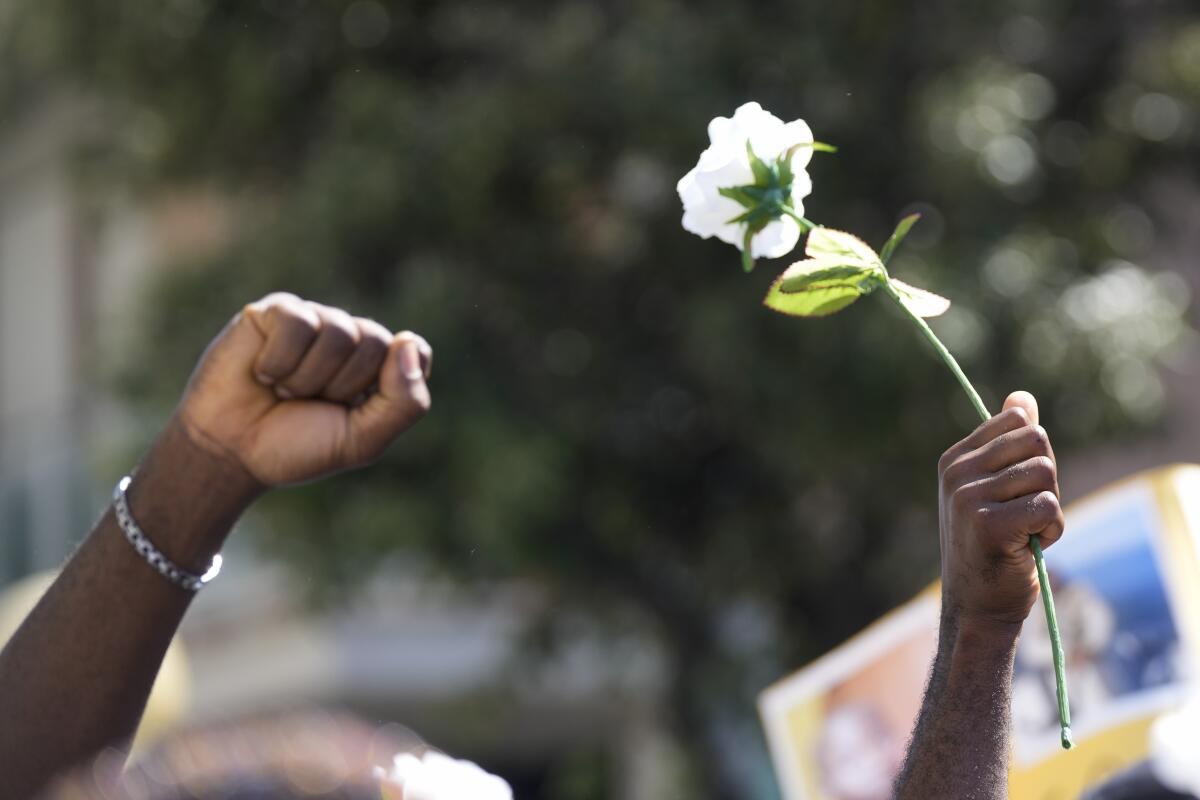 A demonstrators holds up a white rose during a protest to demand justice for Nigerian street vendor Alika Ogorchukwu in Civitanova Marche, Italy, Saturday, Aug. 6, 2022. The brutal killing of Ogorchukwu in broad daylight has sparked a debate in this well-to-do Adriatic beach community over whether the attack by an Italian man with a court-documented history of mental illness was racially motivated. (AP Photo/Antonio Calanni)