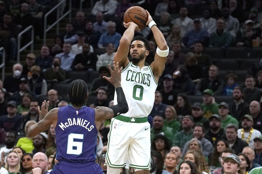 El alero de los Celtics de Boston Jayson Tatum lanza el balón a la distancia para anotar sobre el alero de los Hornets de Charlotte Jalen McDaniels en el encuentro del lunes 28 de noviembre del 2022. (AP Foto/Steven Senne)