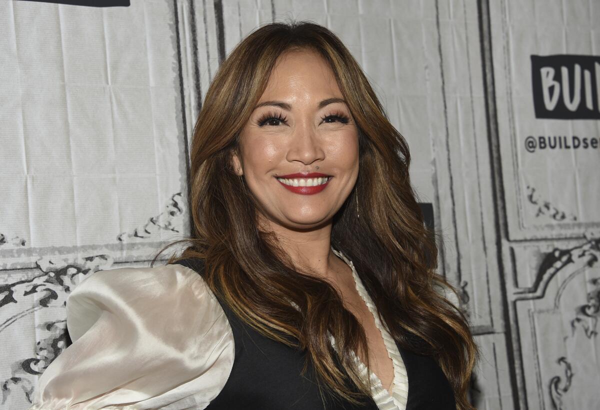 Carrie Ann Inaba smiles in a cream silk blouse and black vest