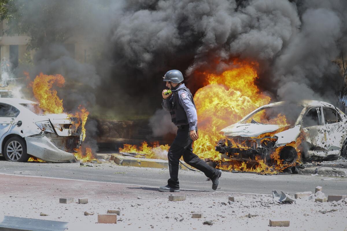 Israeli firefighter next to cars ablaze