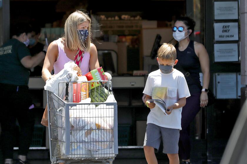 Shoppers walk out of a Sprouts market in Costa Mesa on Monday. People can now face a $100 fine if not wearing a mask in public in the city of Costa Mesa.