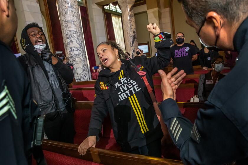 Los Angeles , CA - January 17: Michael Williams, left, and Black Lives Matter co-founder Melina Abdullah protest the presence of city council Kevin de Leon at the city council meeting at City Hall on Tuesday, Jan. 17, 2023 in Los Angeles , CA. (Irfan Khan / Los Angeles Times)