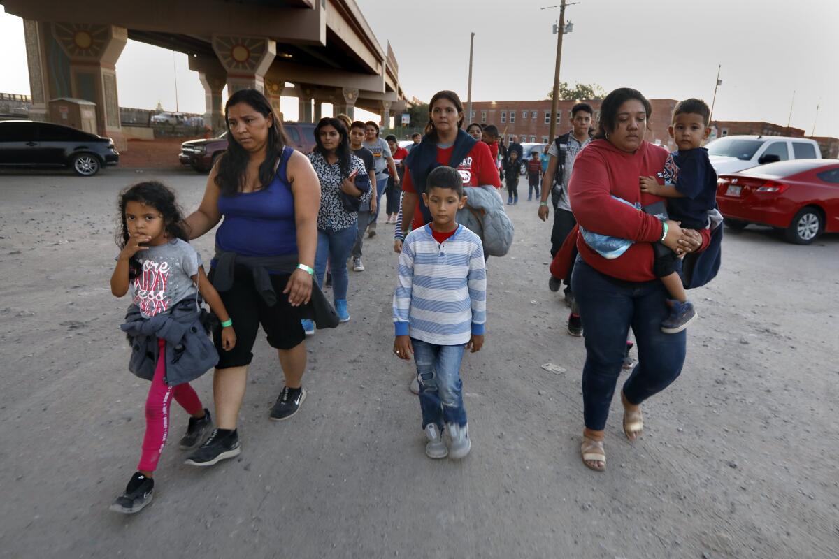A group of about 50 migrants are led by U.S. Border Patrol agents and police officers to a holding area in El Paso after they crossed into the United States to seek political asylum.