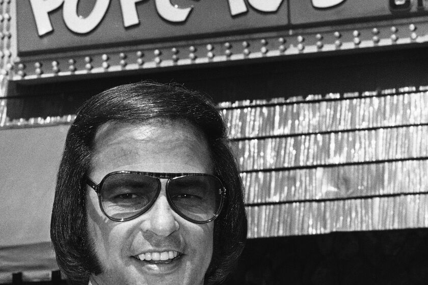 FILE - Popeyes founder Al Copeland holds a piece of his fried chicken outside one of his 34 fast food outlets in New Orleans on June 20, 1979. A new book, “Secrets of a Tastemaker: Al Copeland, The Cookbook," released last month, helped mark the 50th anniversary of Popeyes Famous Fried Chicken. (AP Photo, File)