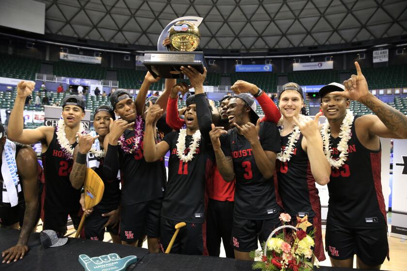 Houston players hoist the Diamond Head Classic trophy after defeating Washington 75-71 in an NCAA college basketball game Wednesday, Dec. 25, 2019, in Honolulu. (AP Photo/Marco Garcia)