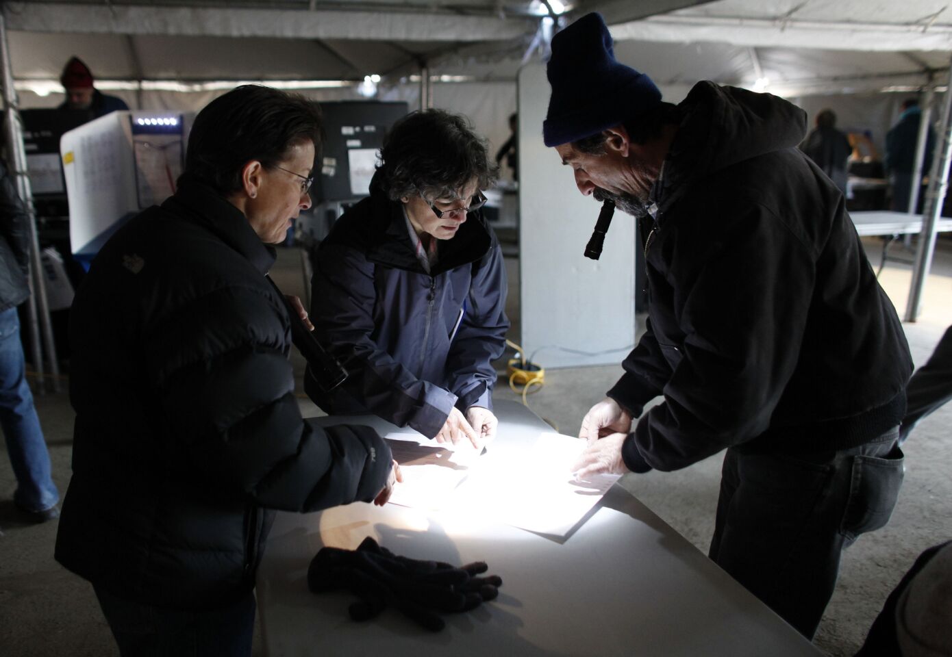 Election workers help a voter, right, finalize his affidavit ballot at a consolidated polling station for residents of the Rockaways on Election Day in the Queens borough of New York.