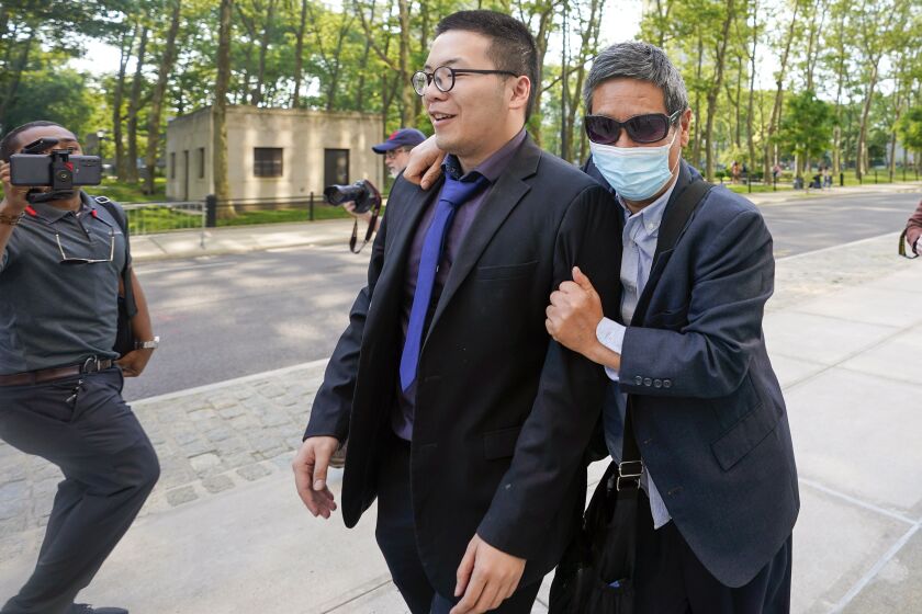 Zhu Yong, right, tries to shield himself from photographers as he leaves Brooklyn Federal court, May 31, 2023, in New York. Michael McMahon, Yong and Zheng Congying are charged with being part of a continent-hopping conspiracy to hound a New Jersey man, his wife and their adult daughter. The couple had left their homeland and kept their U.S. address private. Yet eight years later, two strangers were banging on their New Jersey front door and twisting the handle, the wife testified in a U.S. court on Monday, June 5, 2023. (AP Photo/Mary Altaffer, File)