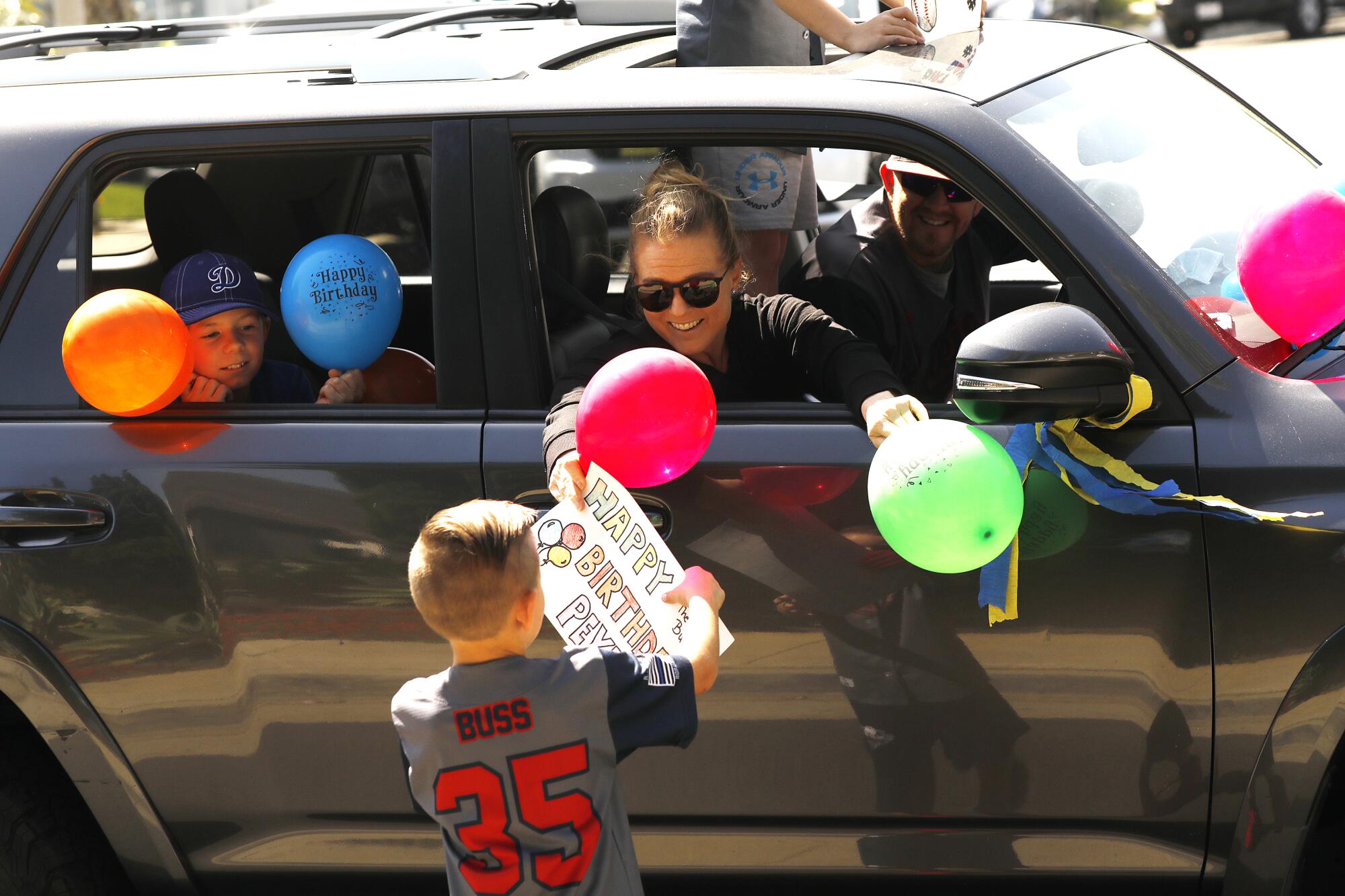 Michelle Buben hands a sign to Peyton to mark his 8th birthday.