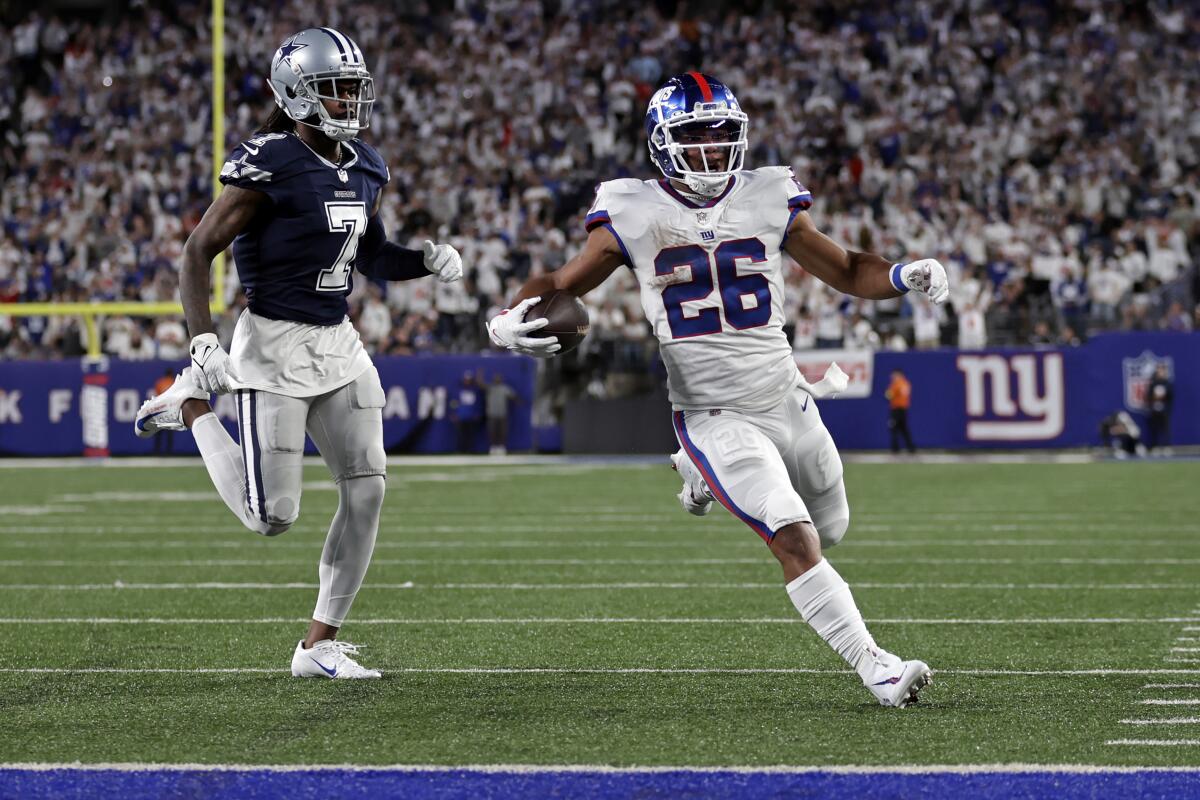 New York Giants running back Saquon Barkley scores a touchdown past Dallas Cowboys cornerback Trevon Diggs.
