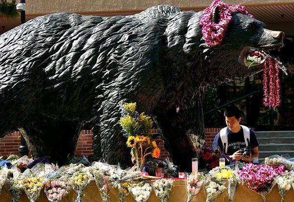 UCLA freshman Austin Quan, 19, pays his respects to the coach at a campus memorial site.