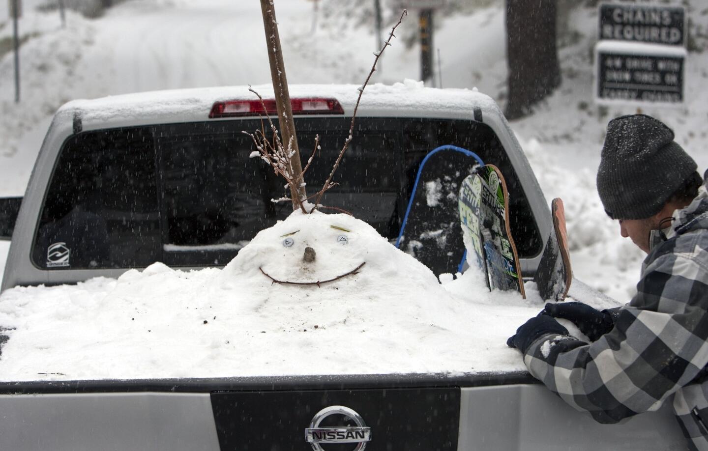 Sebastian Perez of Rancho Cucamonga puts the finishing touches on a snowman face in the back of his pickup truck.
