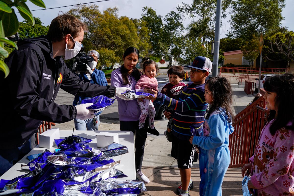 Los Angeles Unified School District board member Nick Melvoin hands headphones to students at the Mar Vista Family Center on Wednesday.