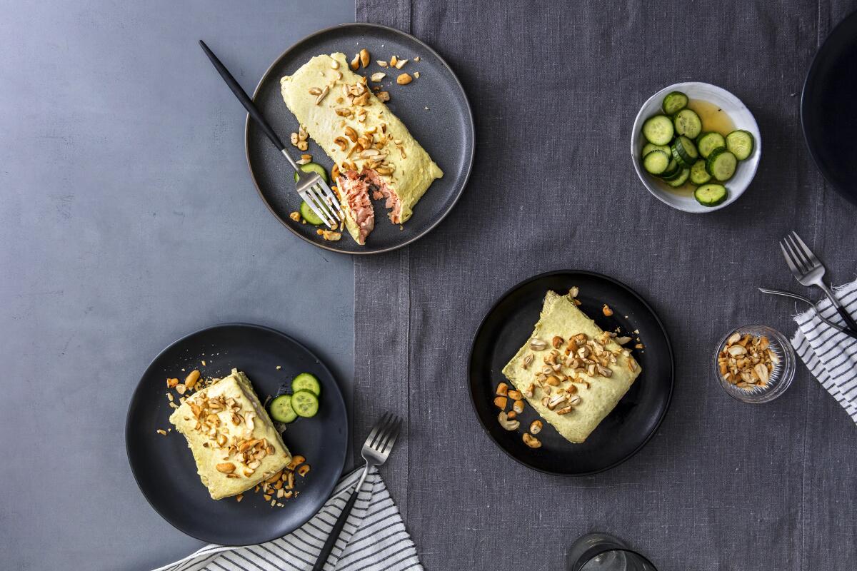 Salmon fillets, baked with a simple topping of green curry paste and Greek yogurt, are served with crunchy salted cucumbers and cashews for a speedy weeknight dinner. 