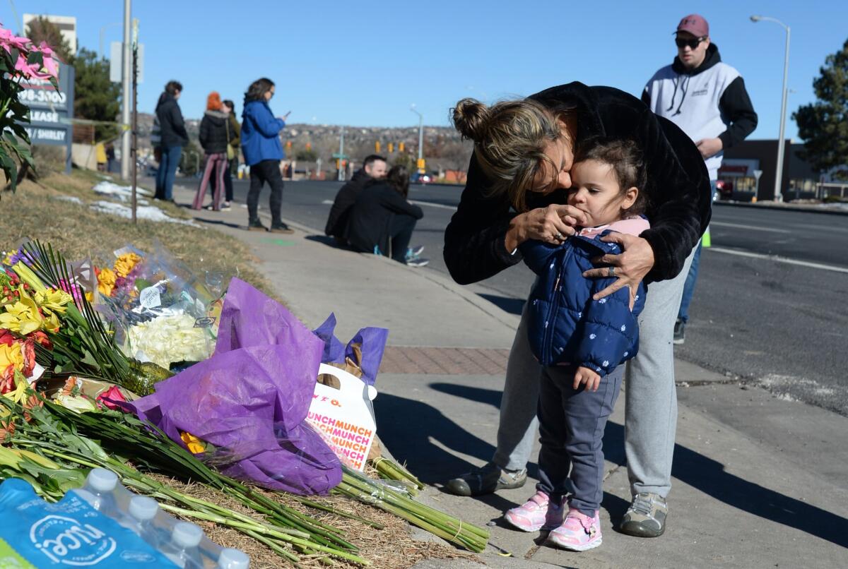 A woman and child on a sidewalk near bouquets on the ground