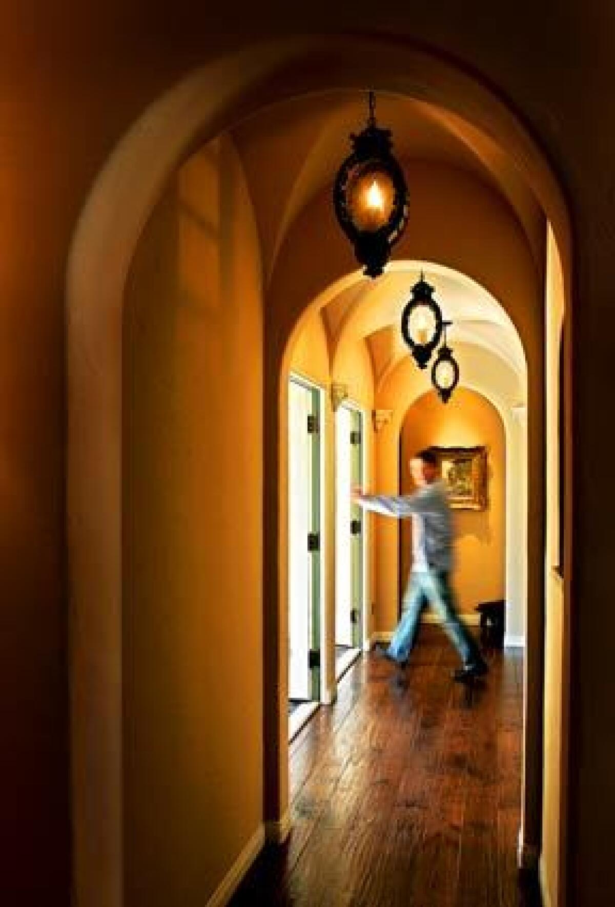 When John and Eva Simpson remodeled their 1920s Spanish Revival home in San Marino, they drew on cultural fusion to create a Spanish style with a twist. Here, John Simpson passes though a hallway with its hand-hewn walnut floors, a groin vault ceiling and custom light fixtures.
