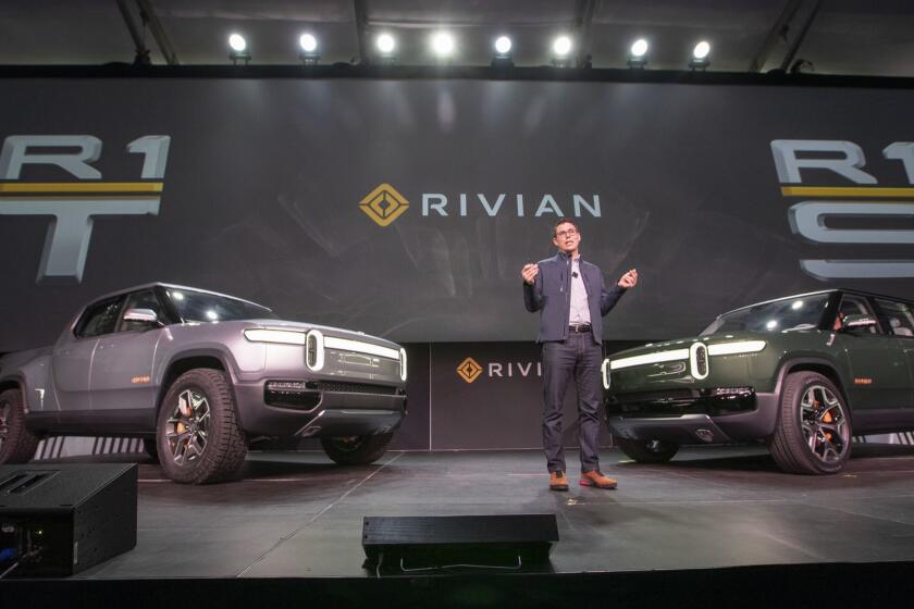 LOS ANGELES, CALIF. -- TUESDAY, NOVEMBER 27, 2018: RJ Scaringe, founder and CEO of Rivian talks during the world premier of their R1S electric SUV, shown at right, and R1T electric truck, left, which are billed as the world?s first electric adventure vehicles during media preview days at the LA Auto Show at the LA Convention Center in Los Angeles, Calif., on Nov. 27, 2018. (Allen J. Schaben / Los Angeles Times)