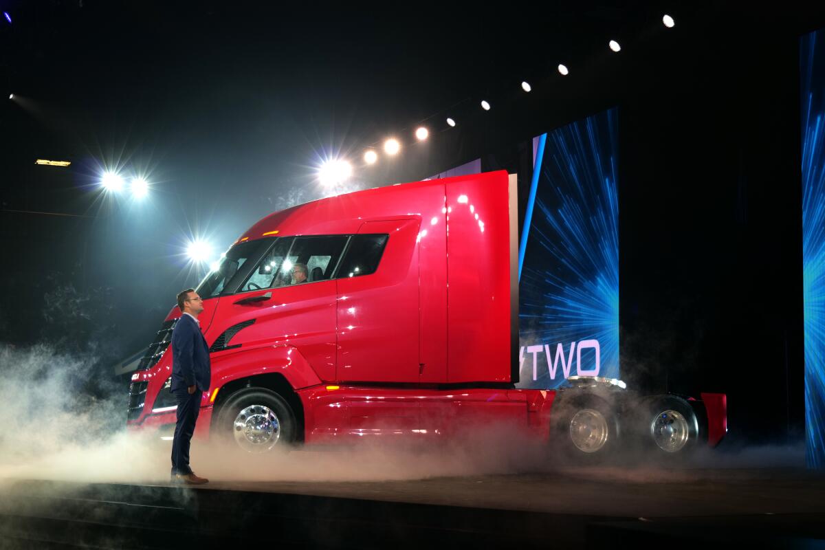 Trevor Milton stands next to a red semi-truck at an unveiling event.