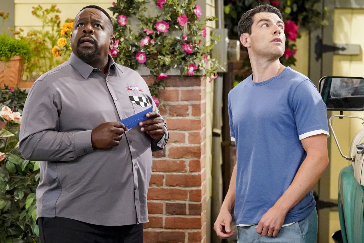 Cedric the Entertainer, left, and Max Greenfield look up in a scene from CBS' "The Neighborhood."