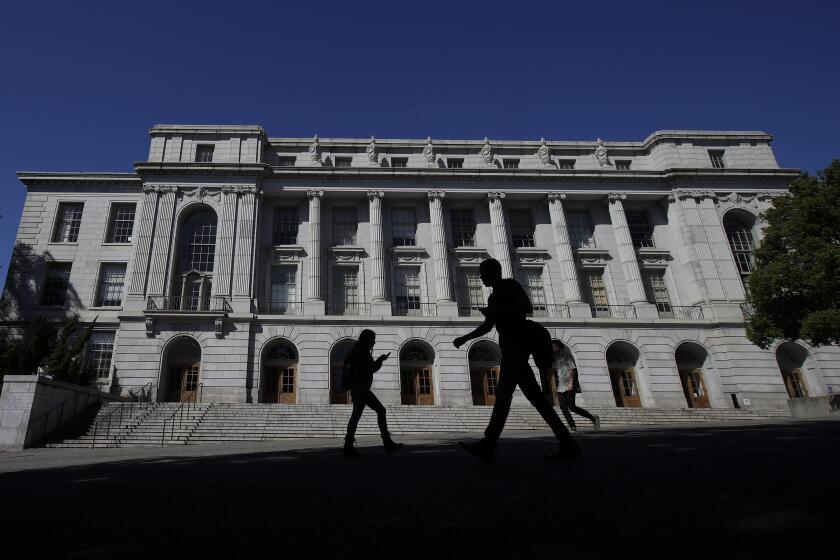 People walk in front of Wheeler Hall on the University of California at Berkeley campus in Berkeley, Calif., Wednesday, March 11, 2020. (AP Photo/Jeff Chiu)