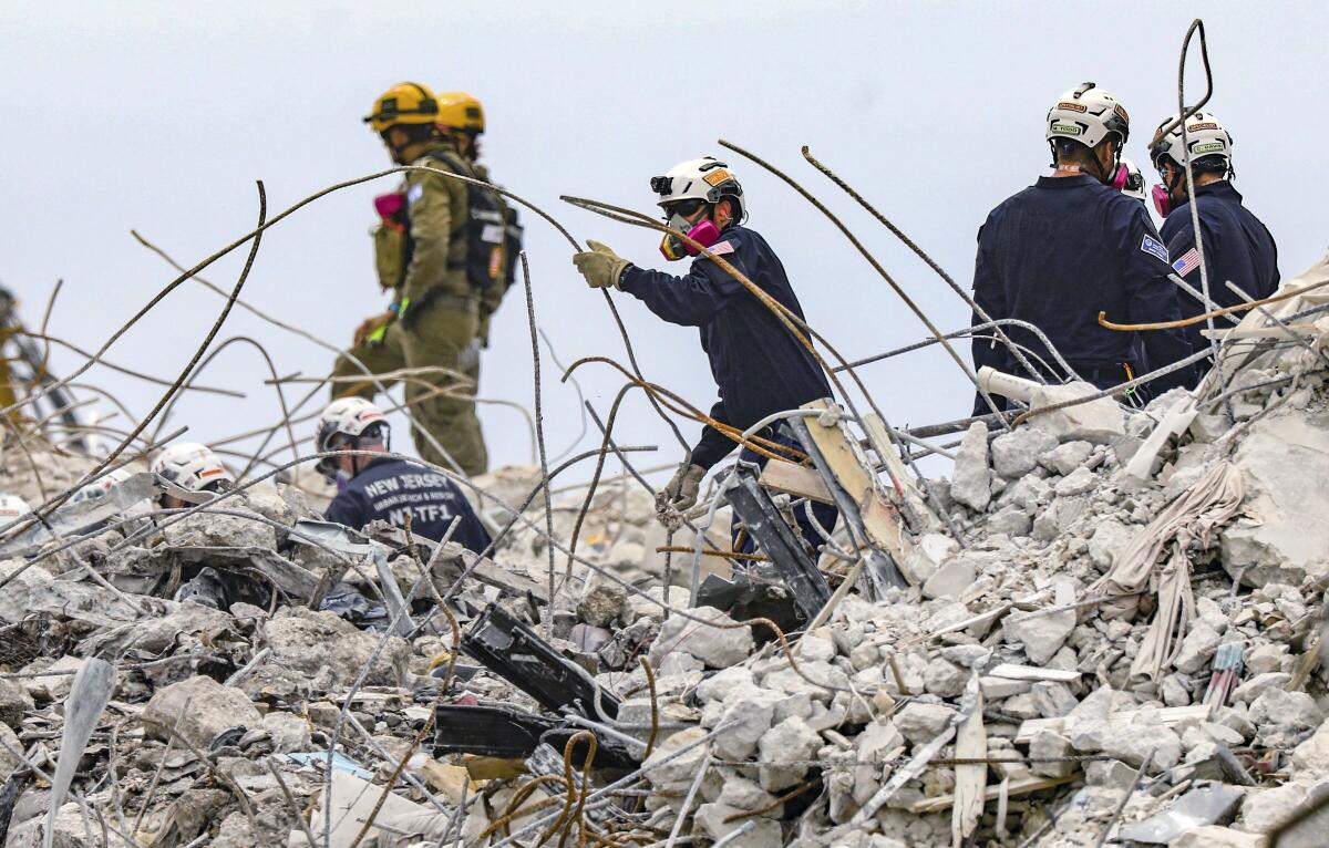 A search and rescue team members dig through the rubble of the Champlain Towers South condo, Wednesday, July 7, 2021. (Al Diaz/Miami Herald via AP)
