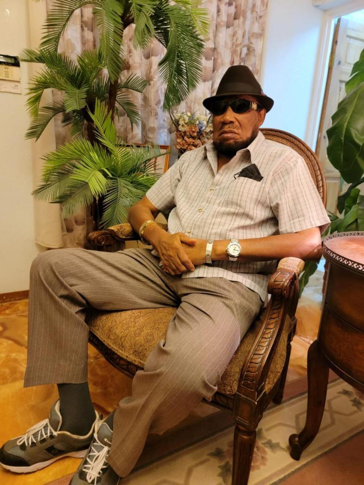 Derrick Morgan sits for portrait wearing his black hat and sunglasses.