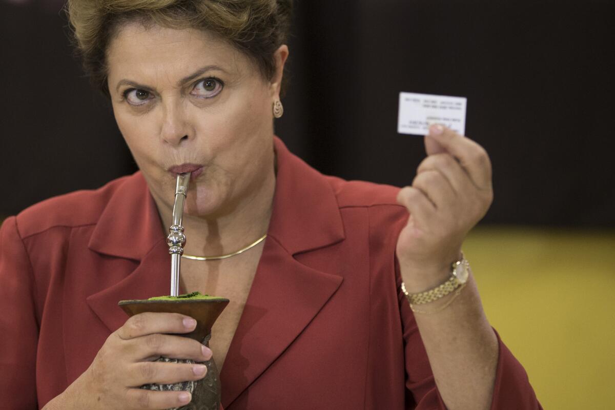 Brazilian President Dilma Rousseff, sipping mate herbal tea, shows her electronic voting receipt Sunday.