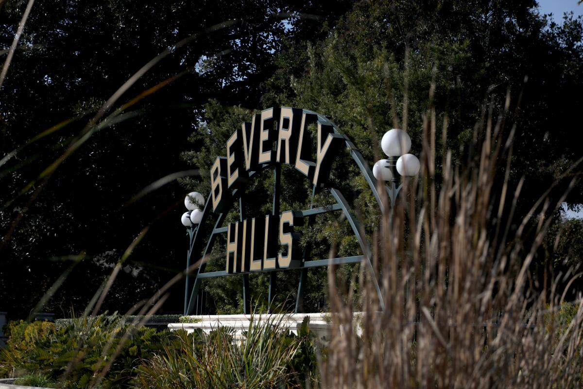A sign reading "Beverly Hills" is in a city park.