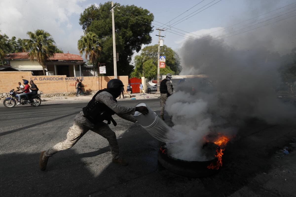 Police put out a burning tire set fire by protesters upset with growing violence in the Lalue neighborhood of Port-au-Prince, Haiti, Wednesday, July 14, 2021. Haitian President Jovenel Moise was assassinated on July 7. (AP Photo/Fernando Llano)