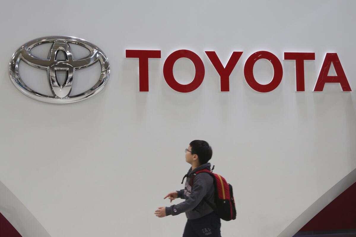 File - A boy looks up at the logo of Toyota Motor Corp. at its gallery in Tokyo, Jan. 15, 2020. Toyota said Tuesday, Nov. 1, 2022, that its profit fell 31% in the last quarter as a shortage of computer chips offset foreign exchange gains from a weaker yen. (AP Photo/Koji Sasahara, File)